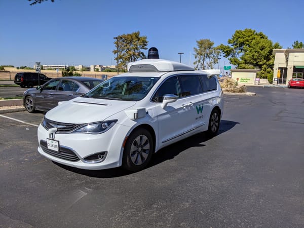 A Waymo Chrysler Pacifica minivan pulled over in a parking lot.